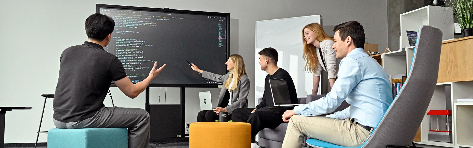 Five Audi employees are talking and looking at something on a screen
