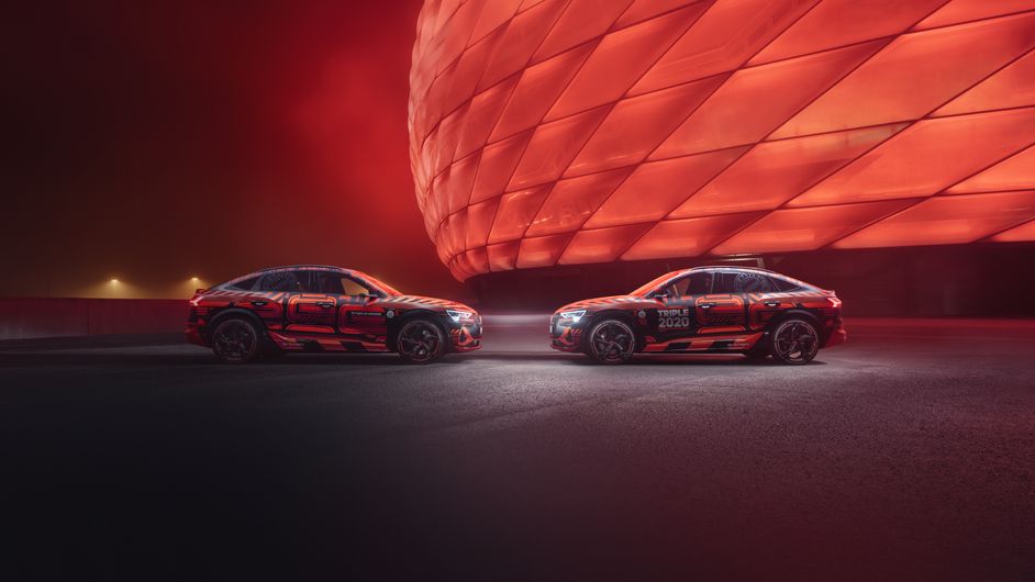 Audi e-tron models in front of the red-lit Allianz Arena