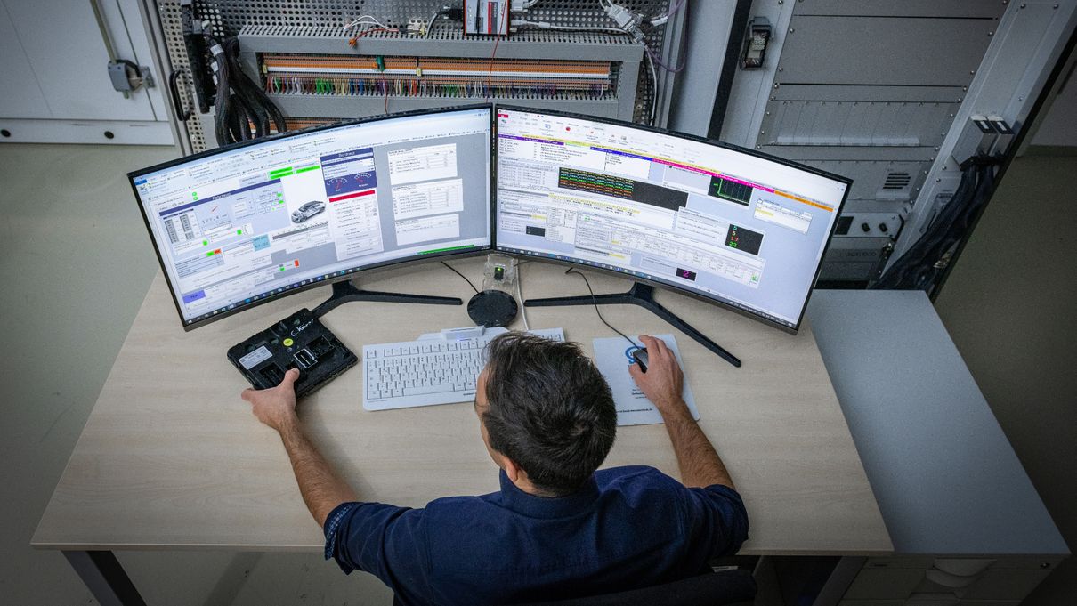 Ein Mann sitzt am Schreibtisch vor zwei Computerbildschirmen