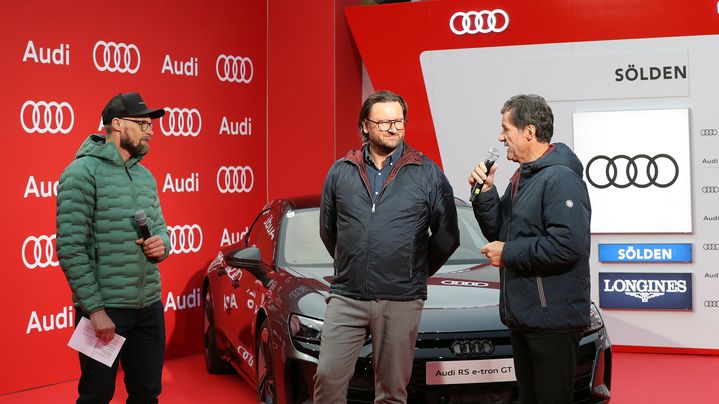 Three men in an interview situation at the FIS Ski World Cup in Sölden. The men are standing in front of a black Audi.
