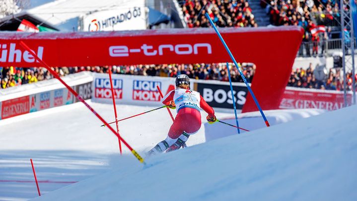 A skier shortly before the finish line. In front of him the red finish arch with the lettering e-tron.