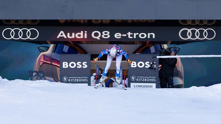 Ein Skifahrer am Start des Abfahrtslaufs. Über ihm steht der Schriftzug Audi Q8 e-tron.