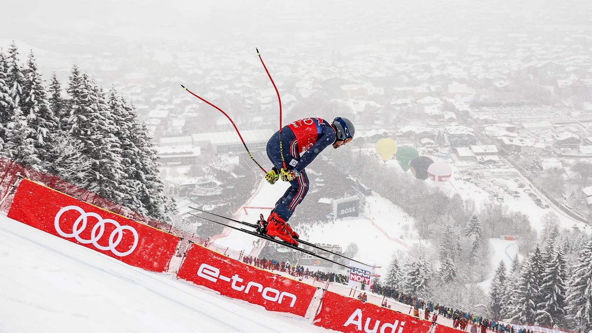 Skifahrer Aleksander Aamodt Kilde im Sprung. Im Hintergrund rote Banden mit dem Audi-Logo und dem Schriftzug e-tron.