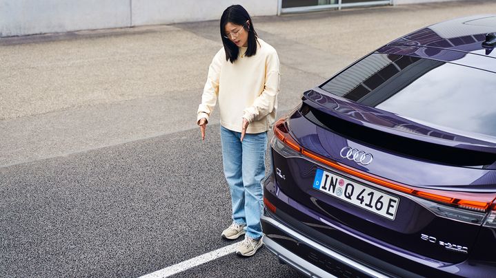 Tiantian explains something and stands next to a purple Audi
