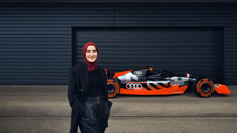 Sümeyye stands smiling in front of the Audi F1 car