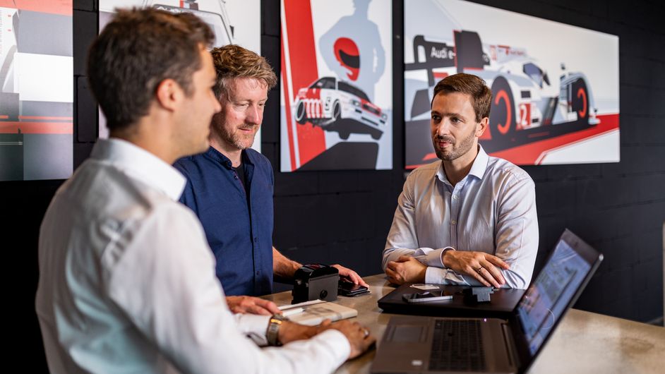 Drei Männer aus dem IT-Bereich der Fahrzeugentwicklung unterhalten sich 