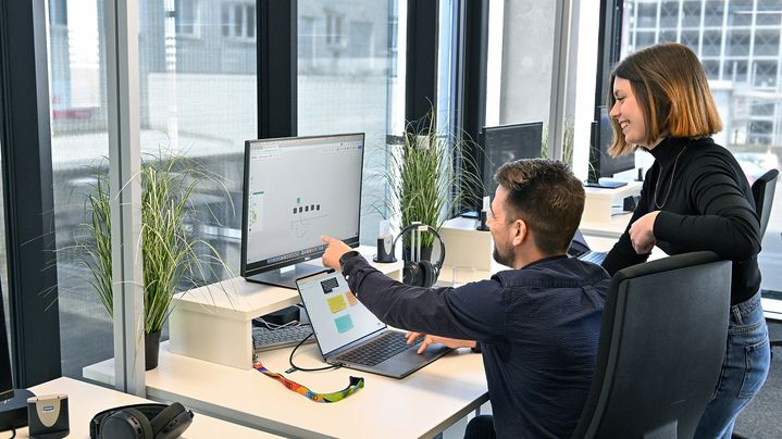 Lisa, Product Designerin SDC, schaut mit einem Kollegen auf einen Computer-Bildschirm