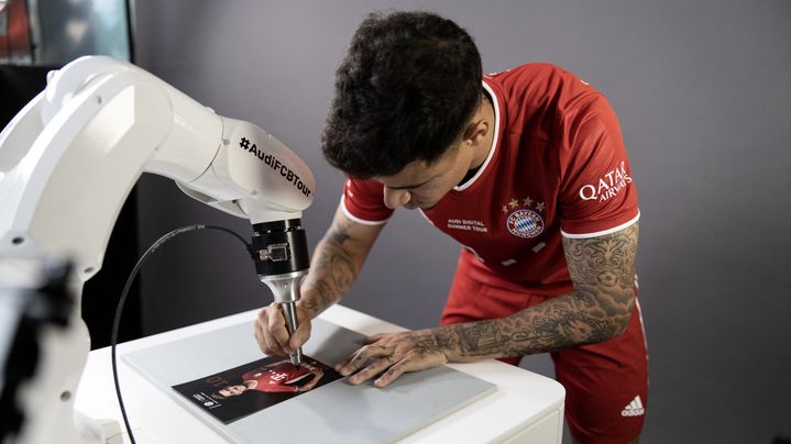 Coutinho unterschreibt Autogrammkarten mithilfe eines Roboterarms.