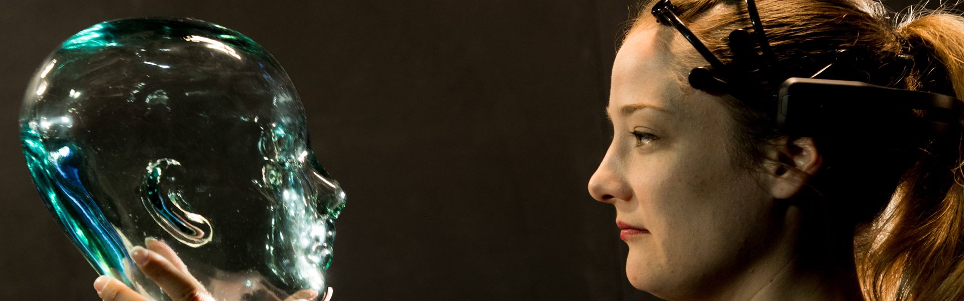 Frau hält gläsernes Modell eines menschlichen Kopfes
