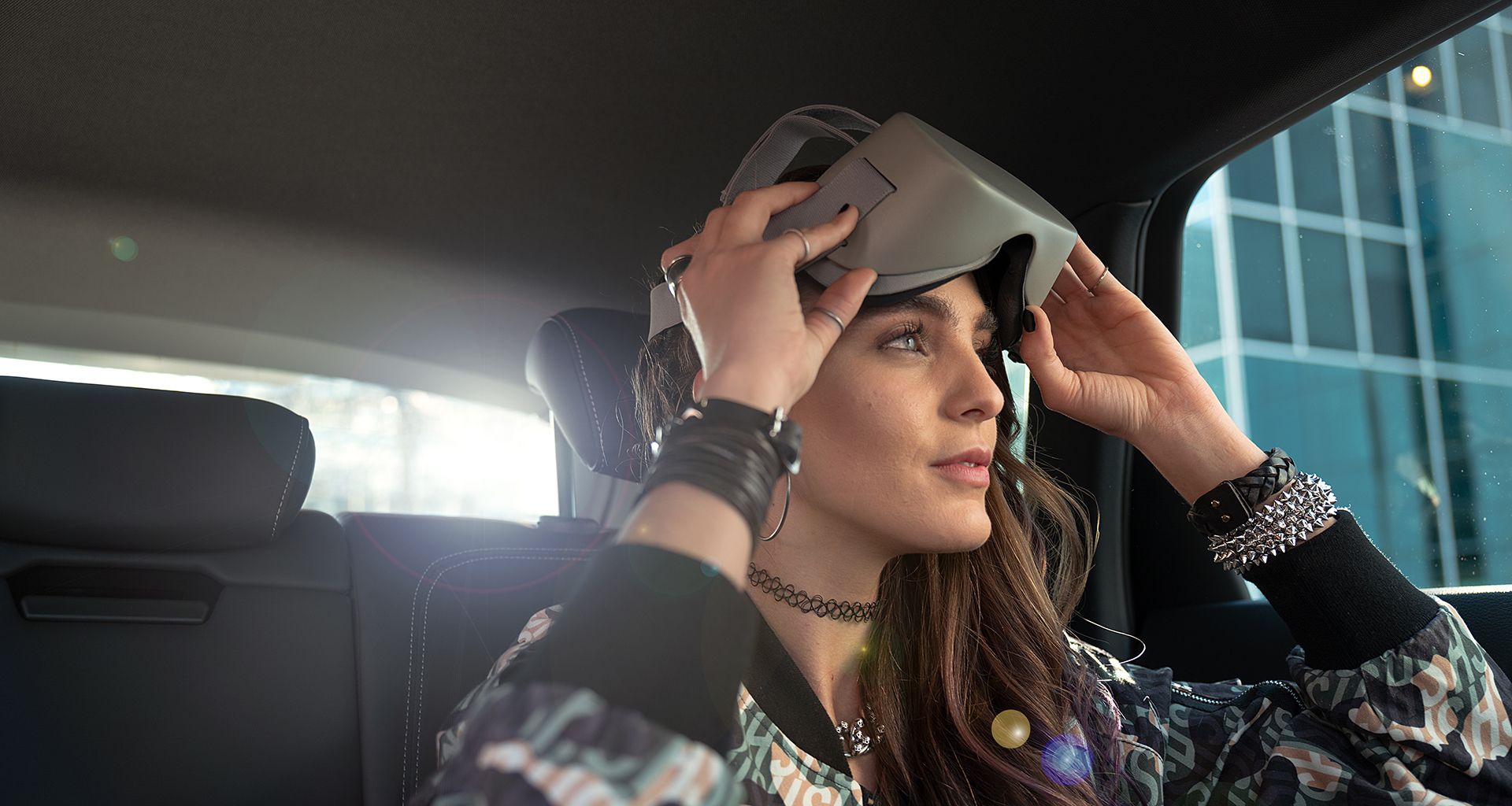 Junge Frau auf der Rückbank eines Audi e-tron mit VR-Brille