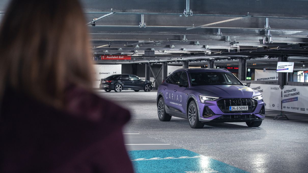 Woman is being picked up by her autonomously driving Audi in the parking garage