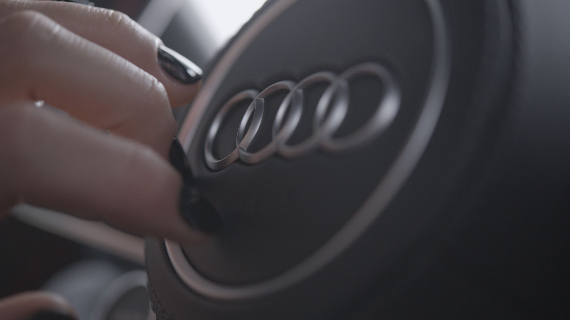 A female hand touching the Audi logo on the steering wheel of an Audi R8 GT
