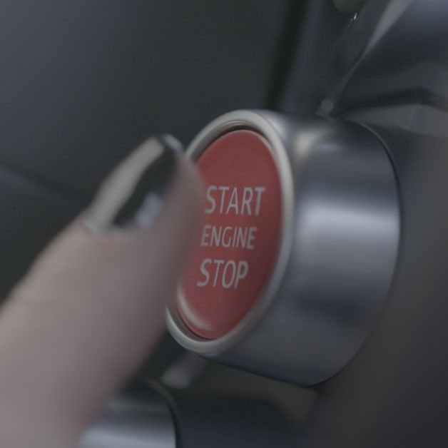 A female hand touching the Start/Stop button inside an Audi R8 GT