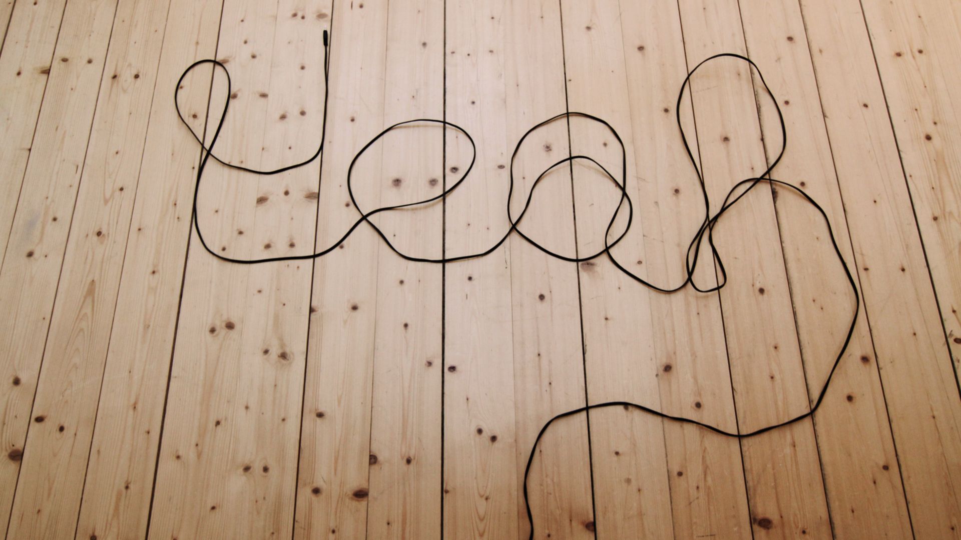 Auf einem Holzboden steht mit einem Kabel geschrieben "yeah"