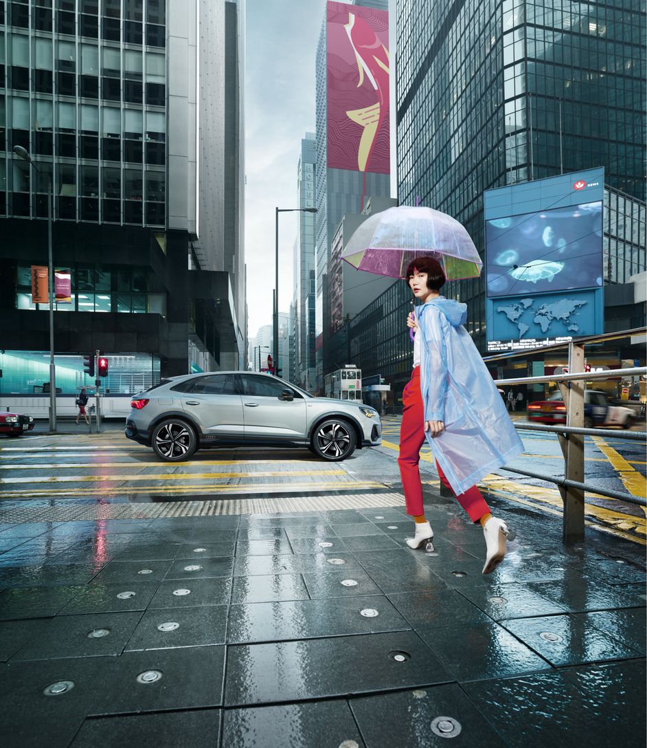 Asiatisch aussehende Frau mit Regenschirm geht nähert sich einem Zebrastreifen
