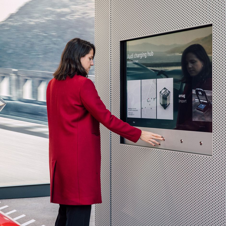 Frau hält eine Karte an den Bedienterminal des Charging Hub in Zürich
