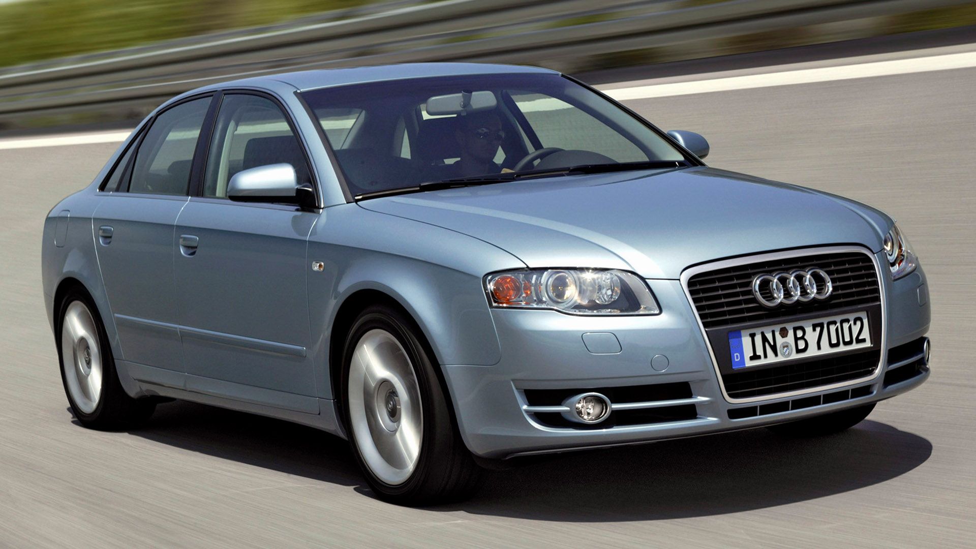Silver-blue Audi A4 sedan driving on the motorway, crash barriers on the side