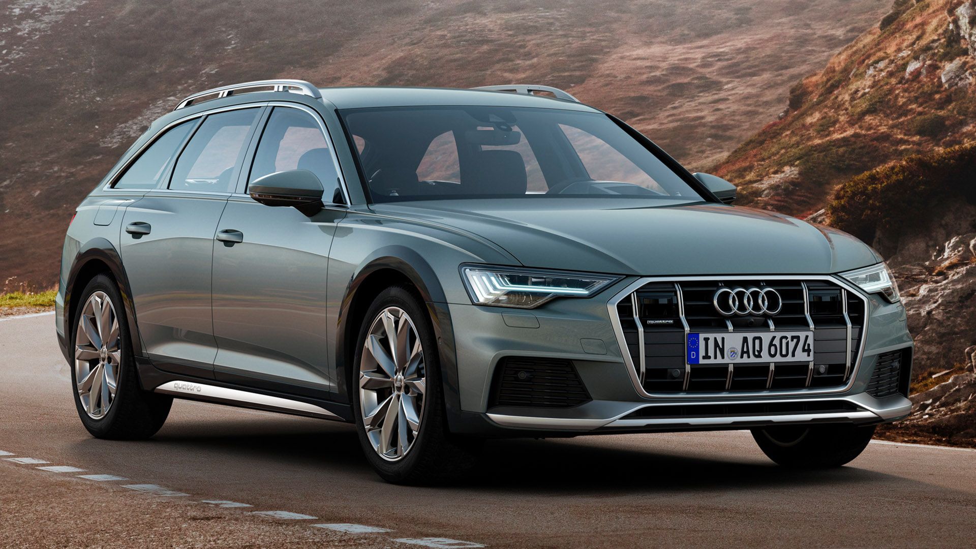 Grey Audi A6 allroad quattro drives on a road in the mountains