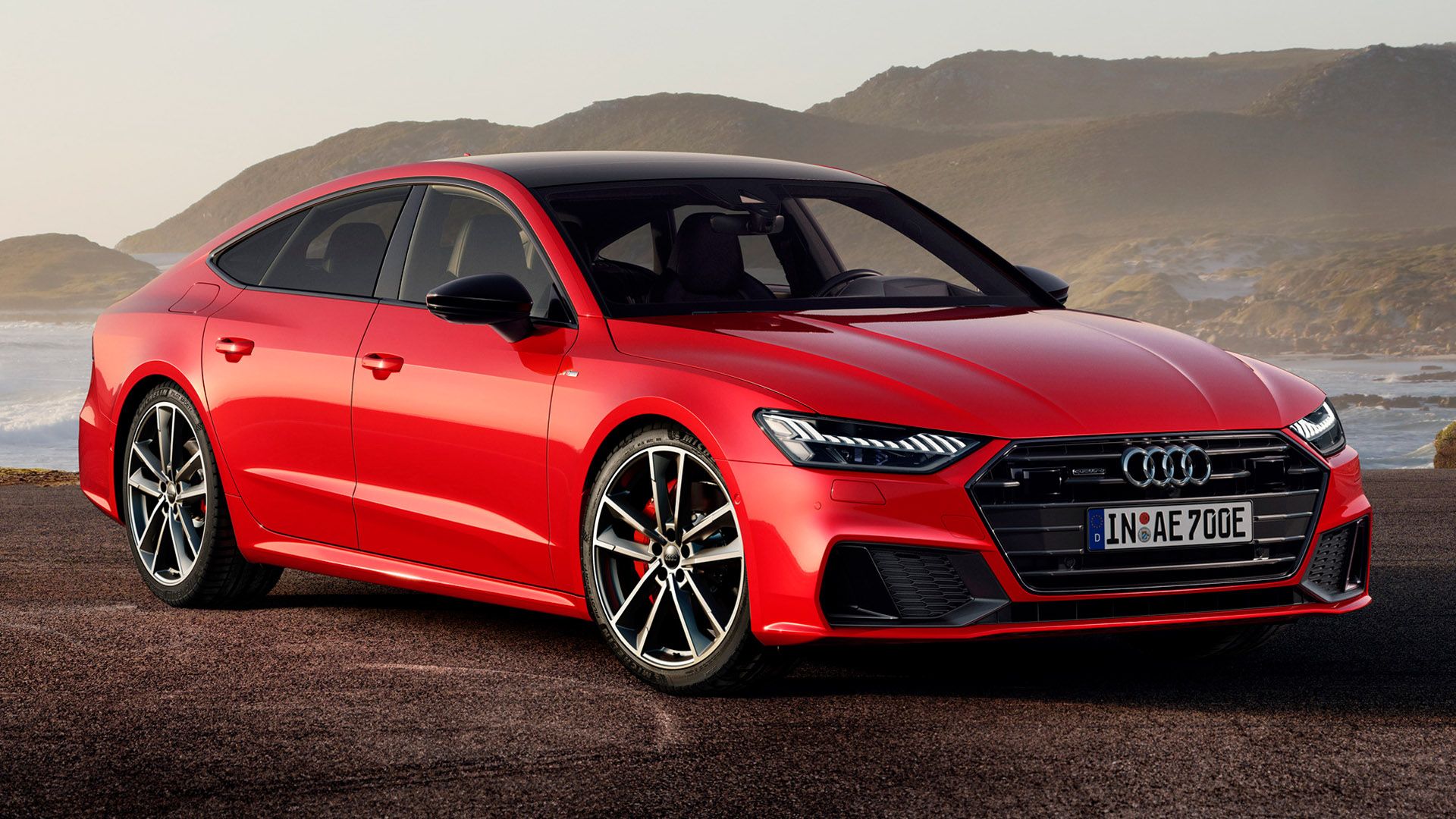 Red Audi A7 Sportback TFSIe, mountains and sea in the background