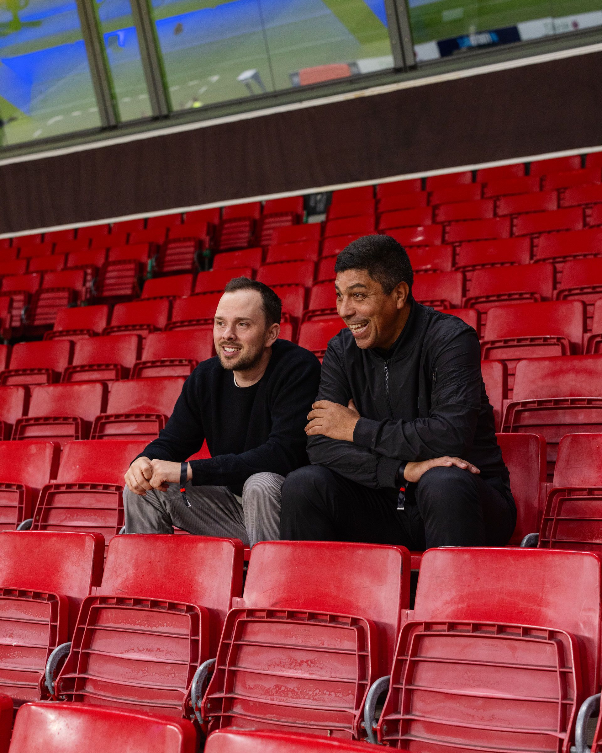 Zwei Männer sitzen im Stadion und lachen