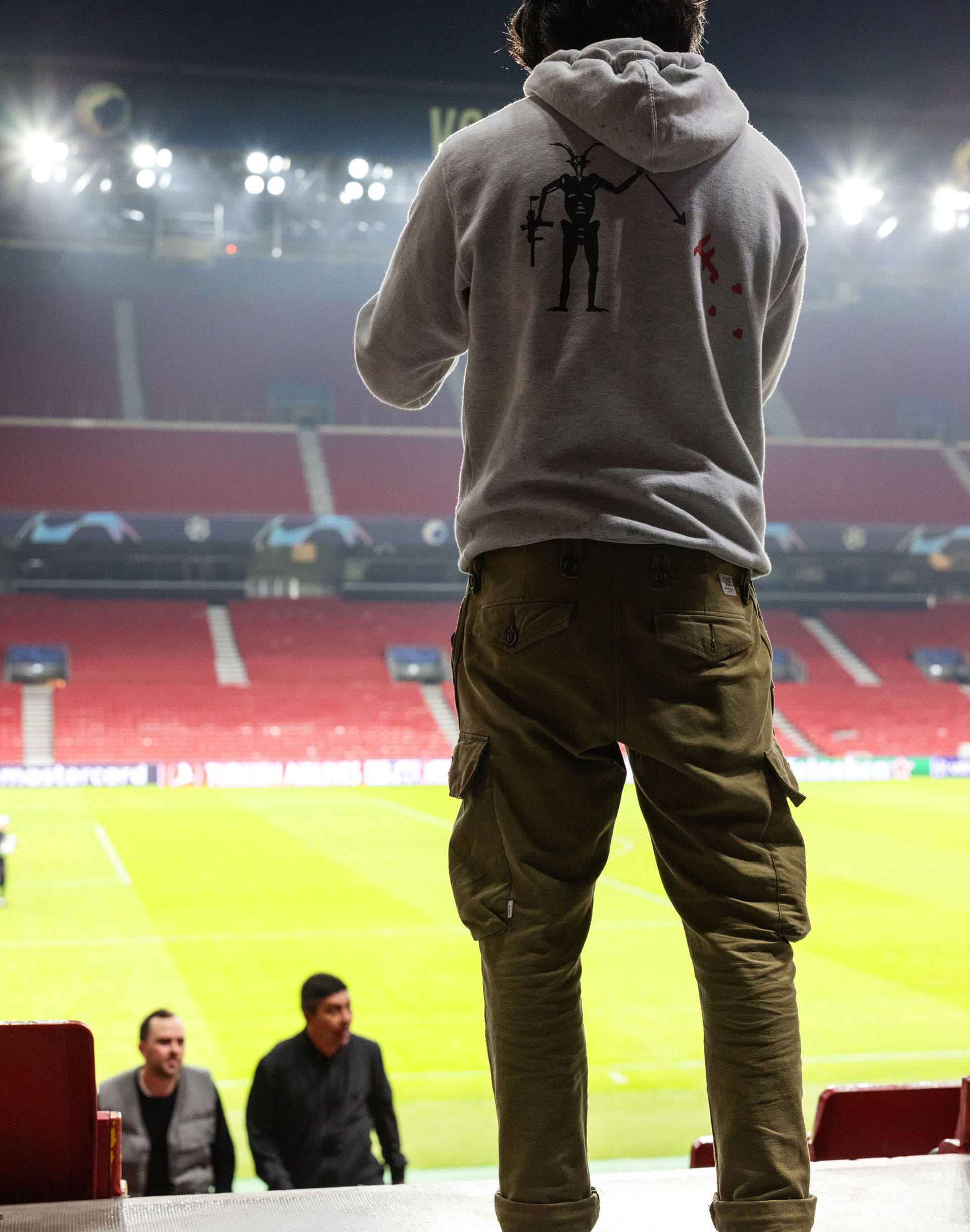 Man standing in stadium with back to camera looking down