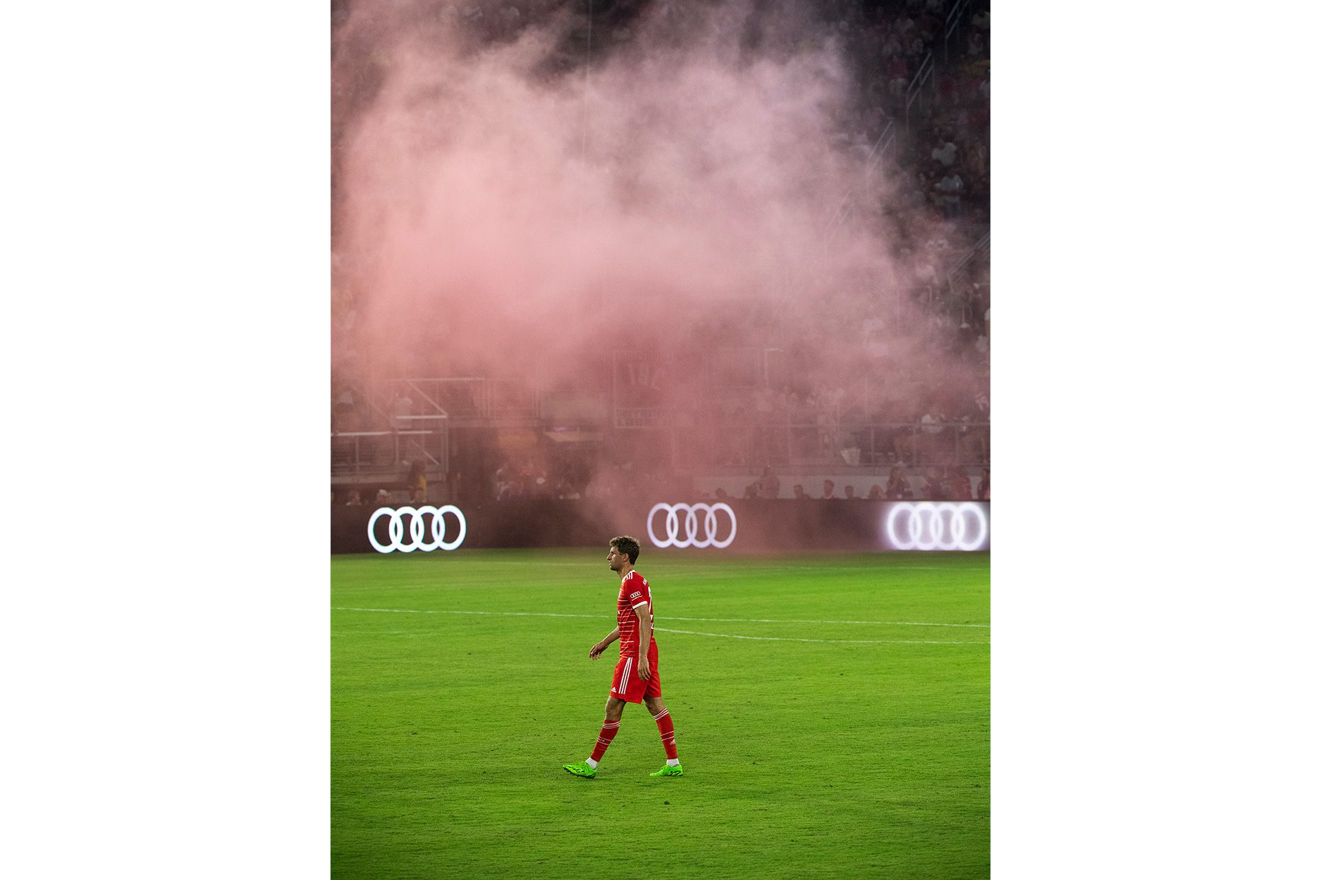 Thomas Müller läuft über das Spielfeld unter einer roten Pyro-Wolke