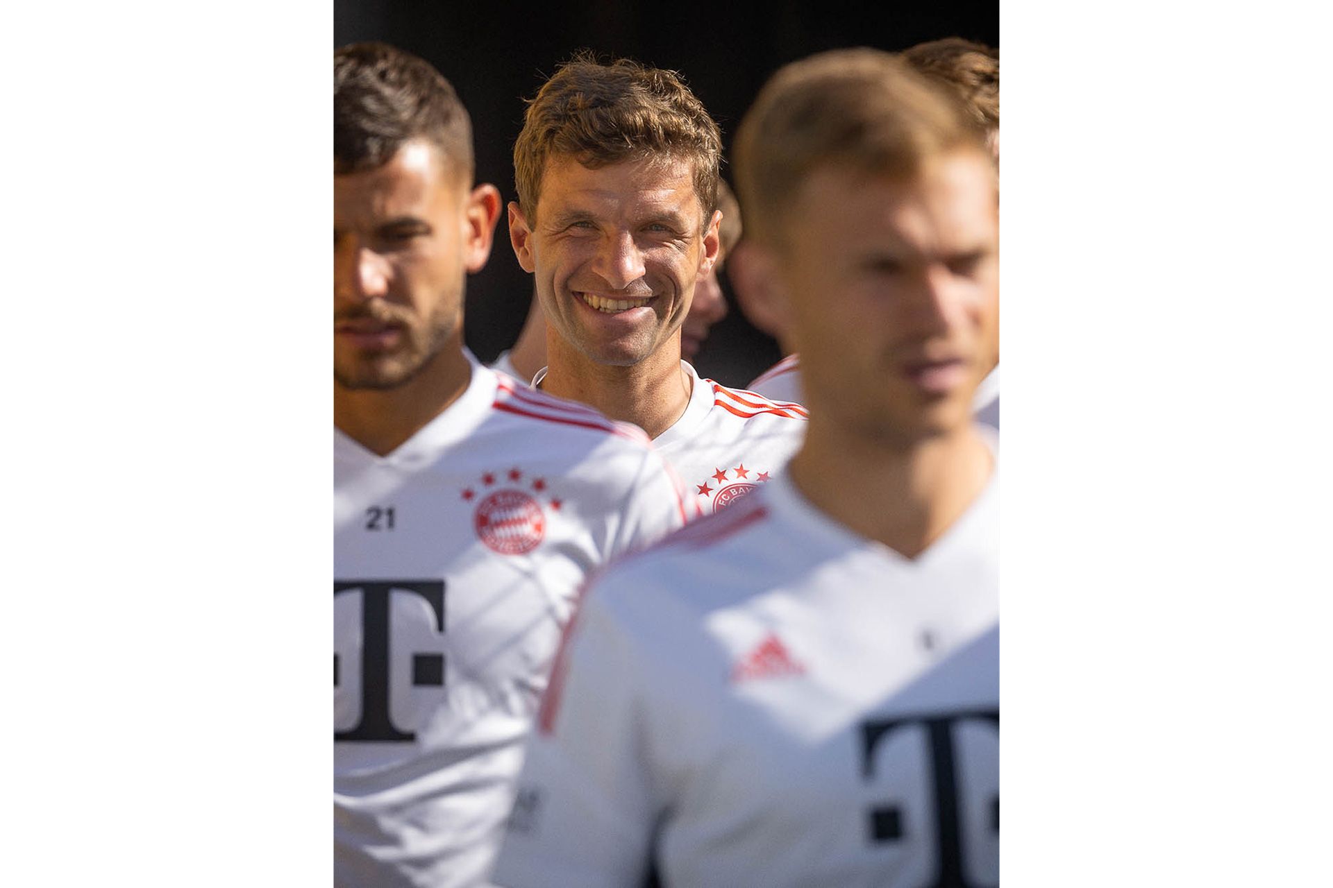 Lachender Thomas Müller zwischen konzentrierten Team-Kollegen während das Team auf das Spielfeld läuft