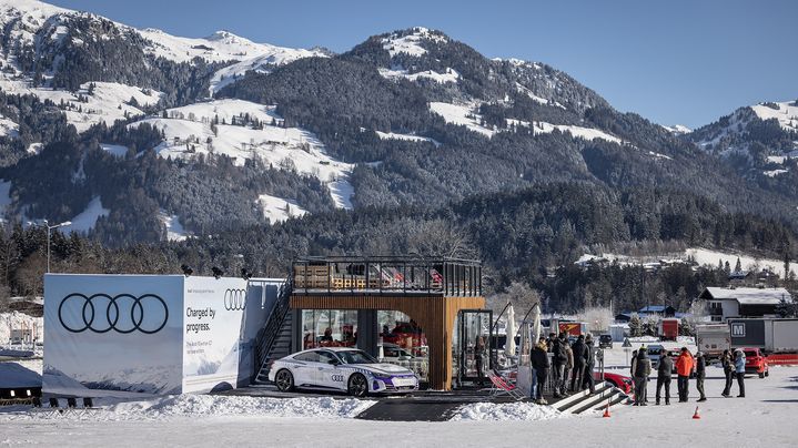 An Audi is parked in front of a pavilion in winter. The mountains can be seen in the background.