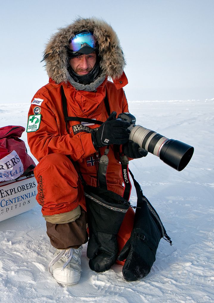 Sebastian Copeland on an expedition in the snow holding his camera. 