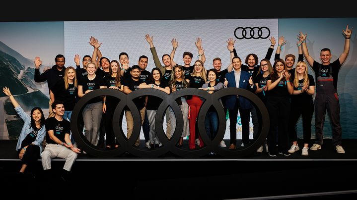 Audi und One Young World Summit Logos über veschwommenem Gruppenbild