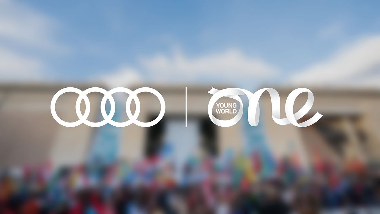 Audi und One Young World Summit Logo über verwischtem Gruppenbild
