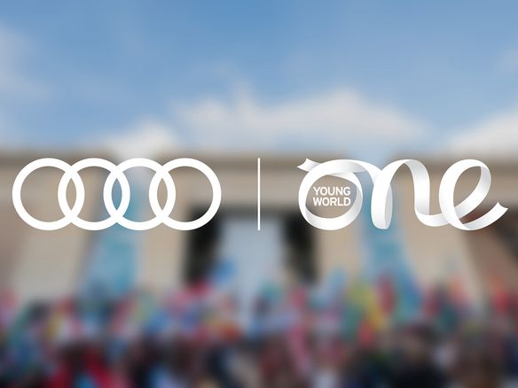 Audi and One Young World Summit logos over blurred group shot
